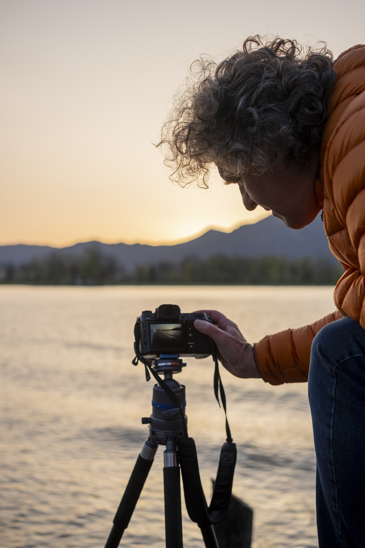 Fotograf Bernd Ritschel mit der Kamera und Stativ an einem Seeufer 