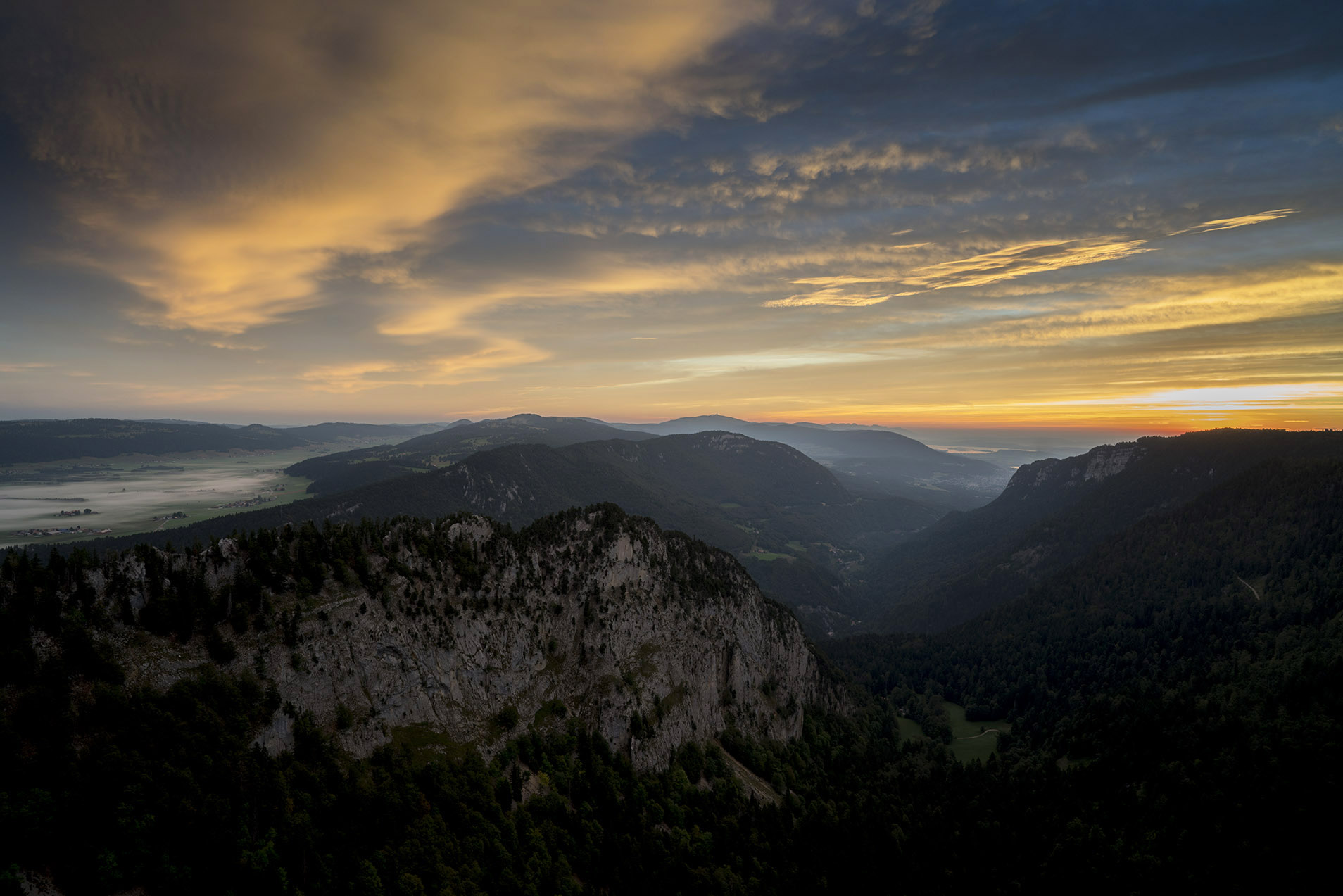 Berg- und Felsketten mit Nebel vor einem orang-blauen Himmel