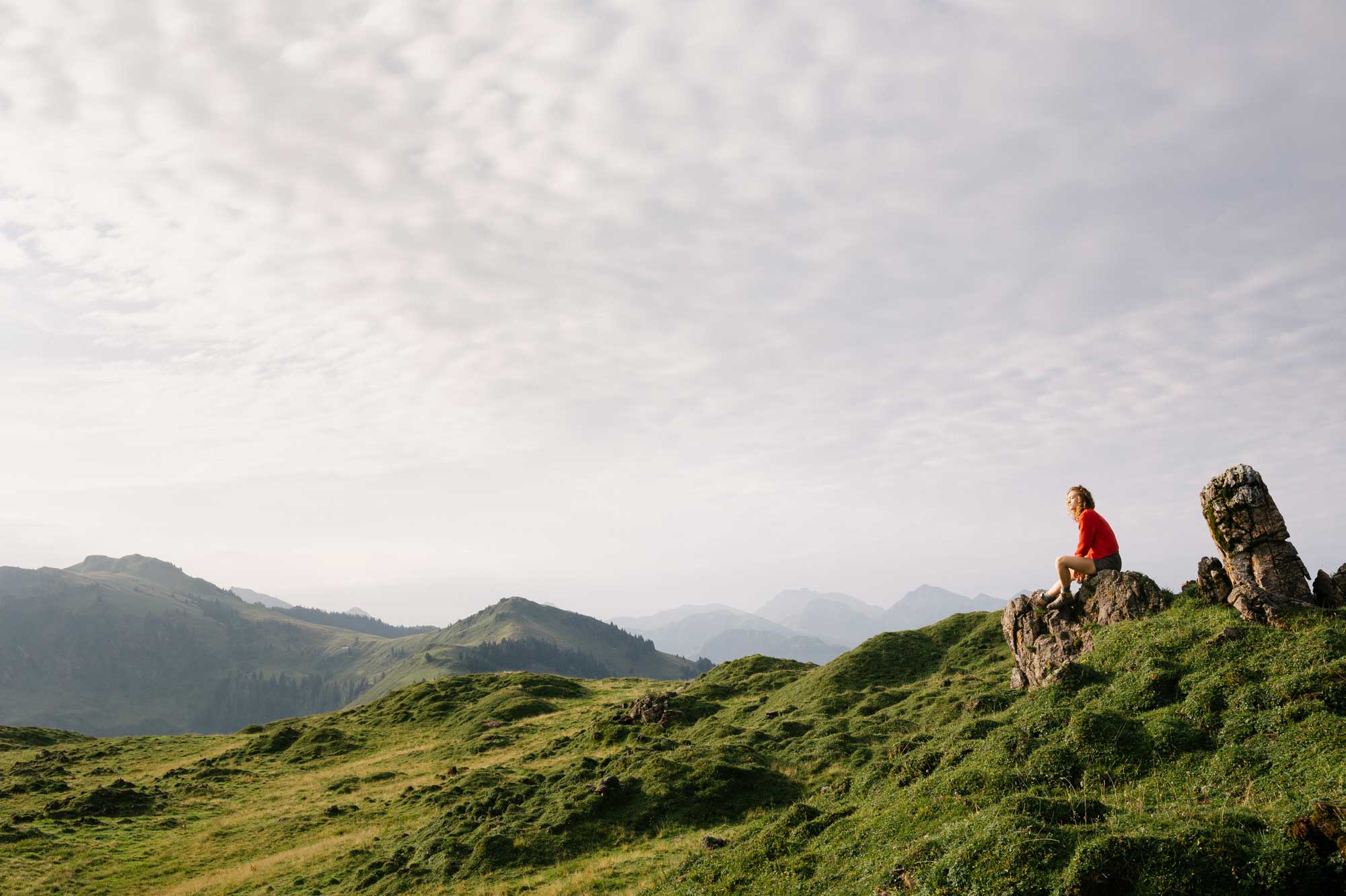 Eine Frau sitzt auf einem Stein in den Bergen
