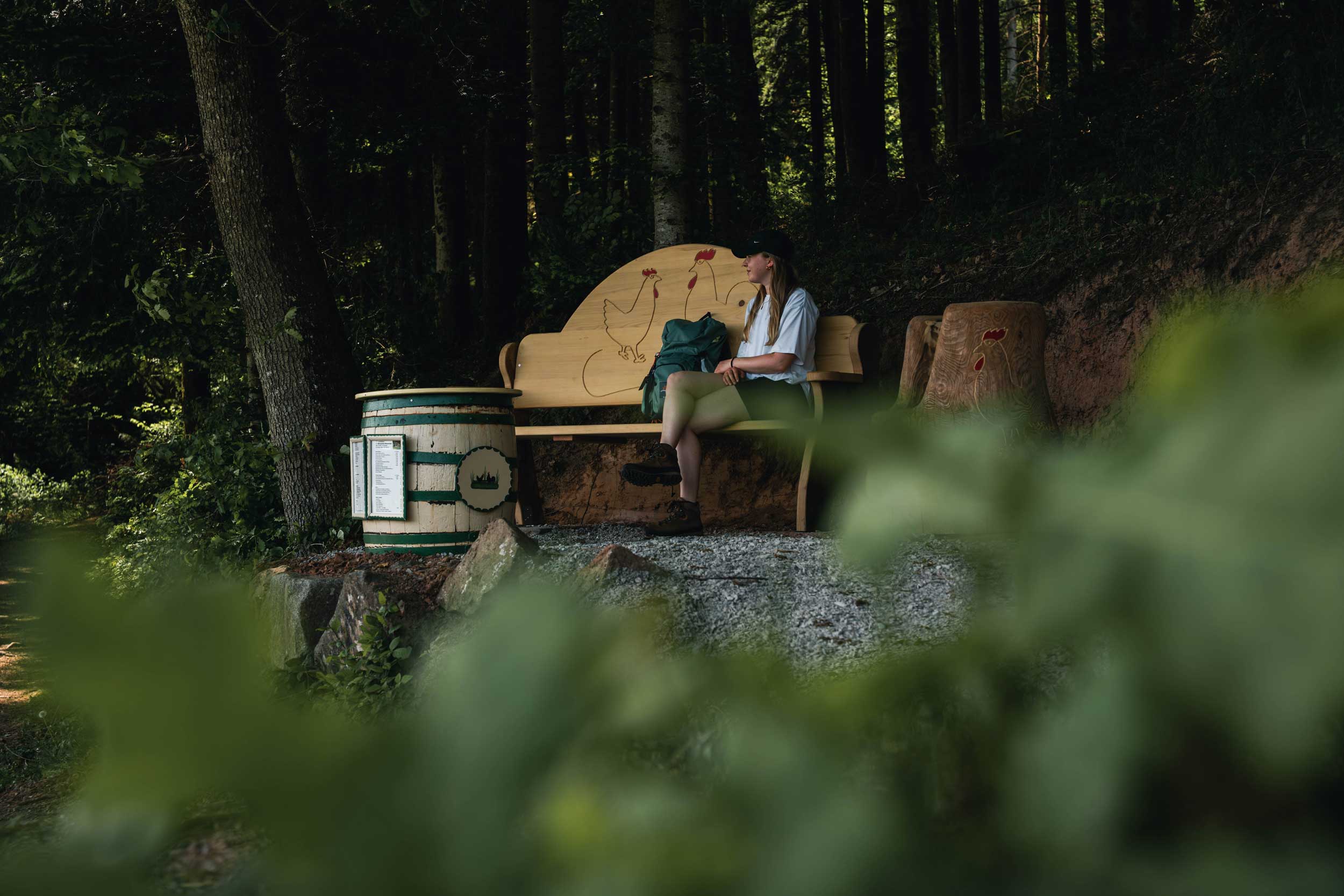 Eine Wanderin sitzt auf einer Bank im Wald