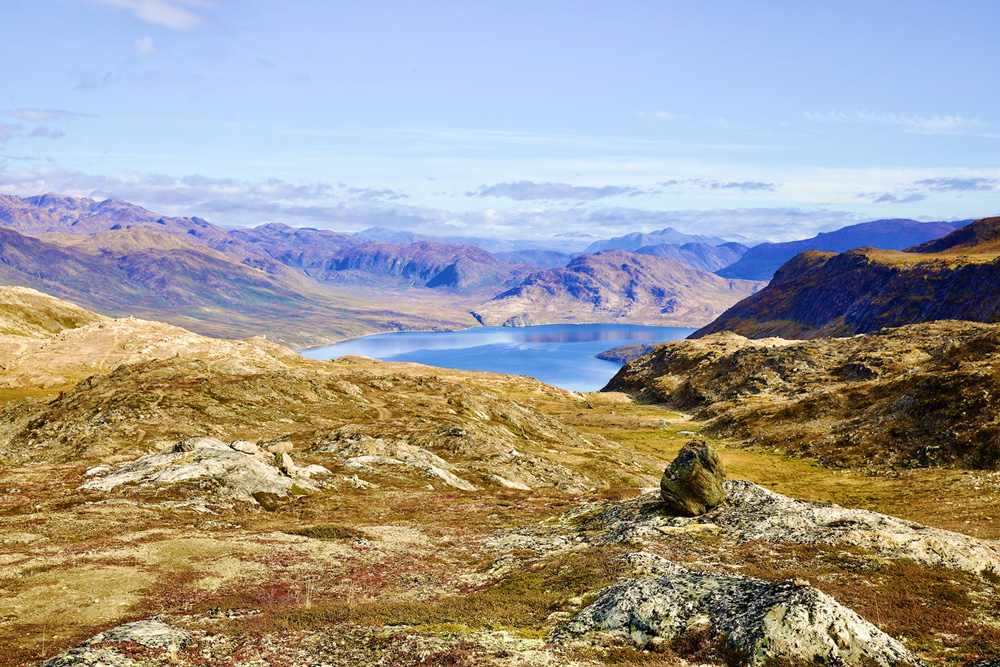 Blick über eine raue Berglandschaft mit einem kleinen See in der Mitte