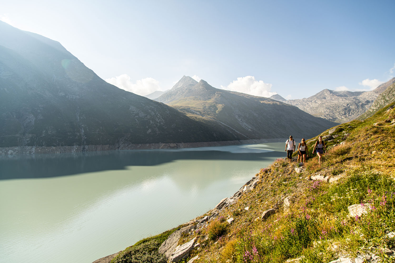 Wandergruppe an Stausee in Bergkulisse