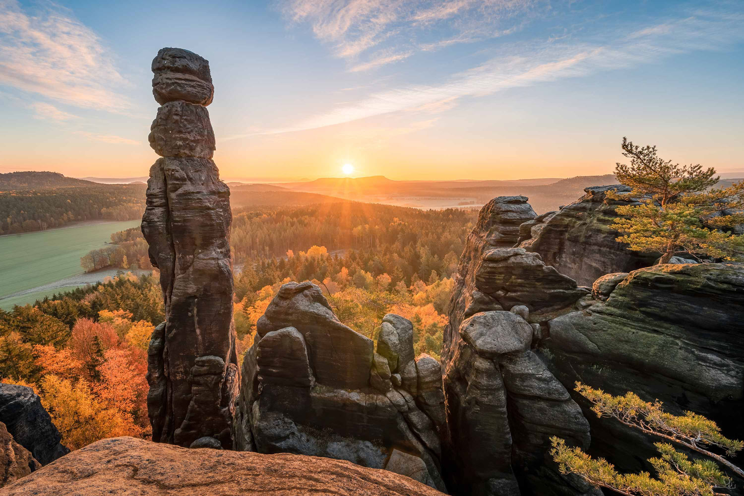 Spitze Felstürme vor einer herbstlichen Hügellandschaft mit goldenem Sonnenlicht