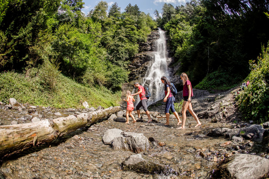 familie wandert an einem Wasserfall vorbei