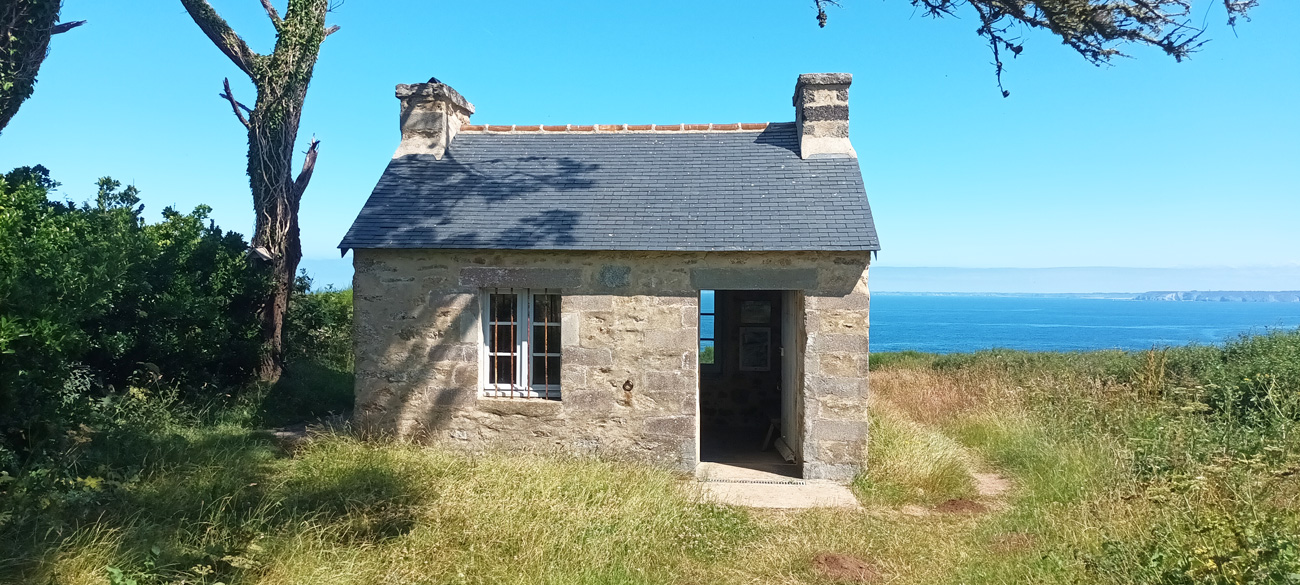 Kleines Haus im Grünen, dahinter liegt das Meer