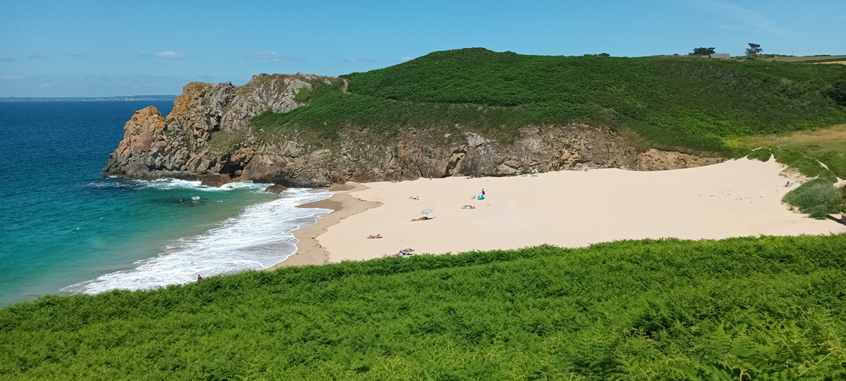 Sandstrand mit türkisblauem Wasser und saftig grünen Klippen
