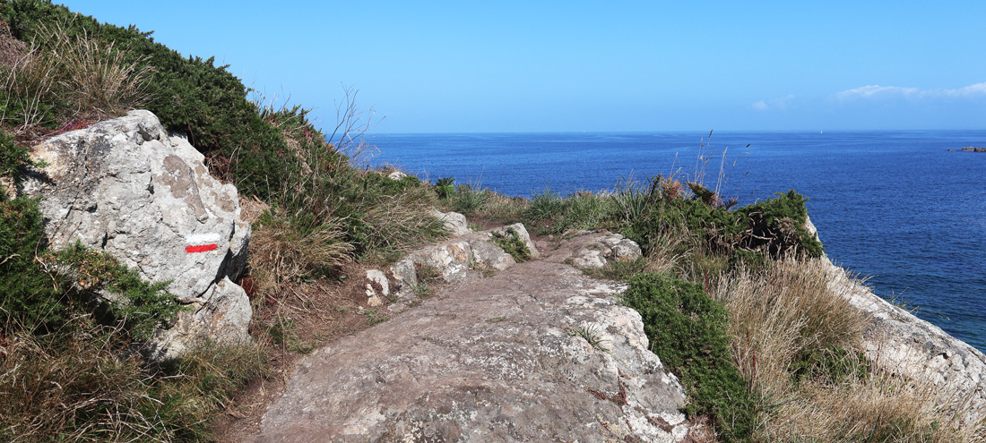 Eine Wegmarkierung auf einem Stein am Wegesrand