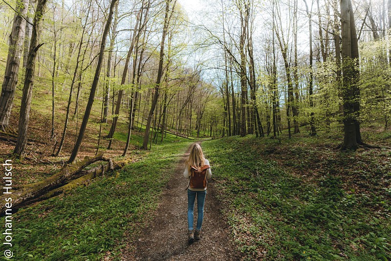 Frau auf einem schmalen Pfad im Wald