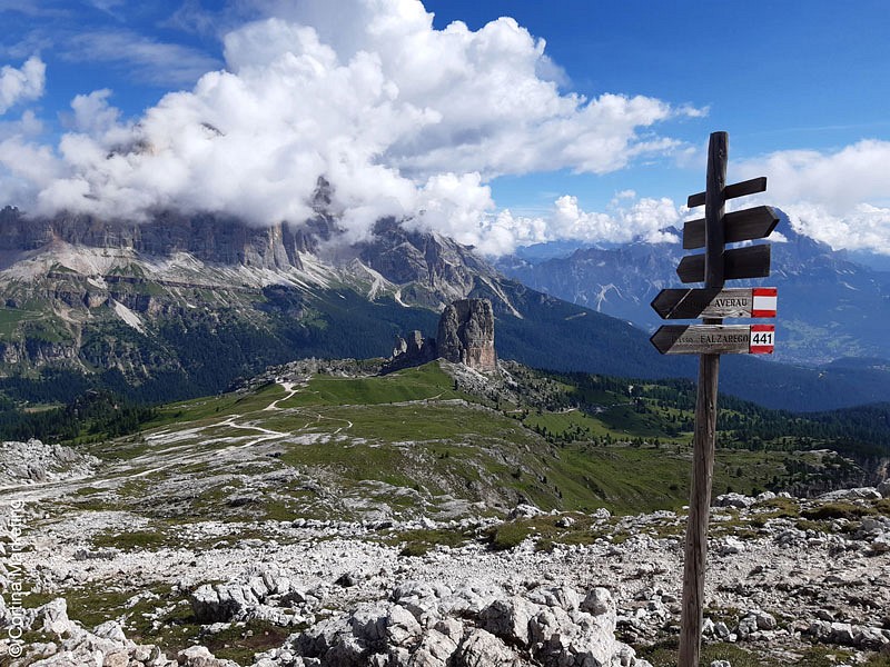 Ein Wegweise vor hellen Steinen und Berggipfeln