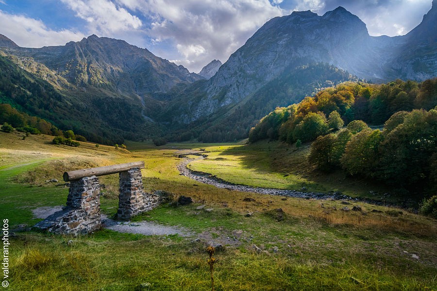 Ein Stück Mauer in einem Flusstal vor einer beeindruckenden, dunklen Bergkulisse