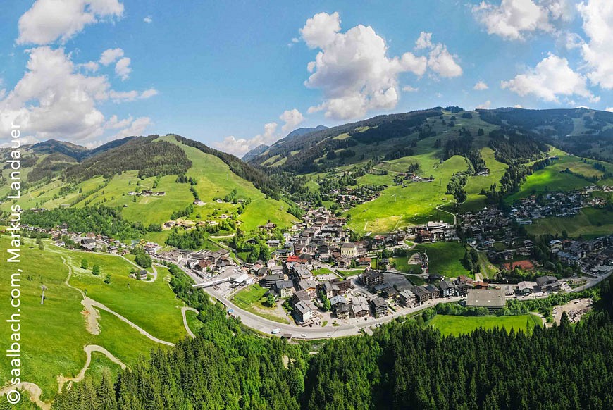 Blick von oben auf Saalbach eingebettet in eine grüne Berglandschaft