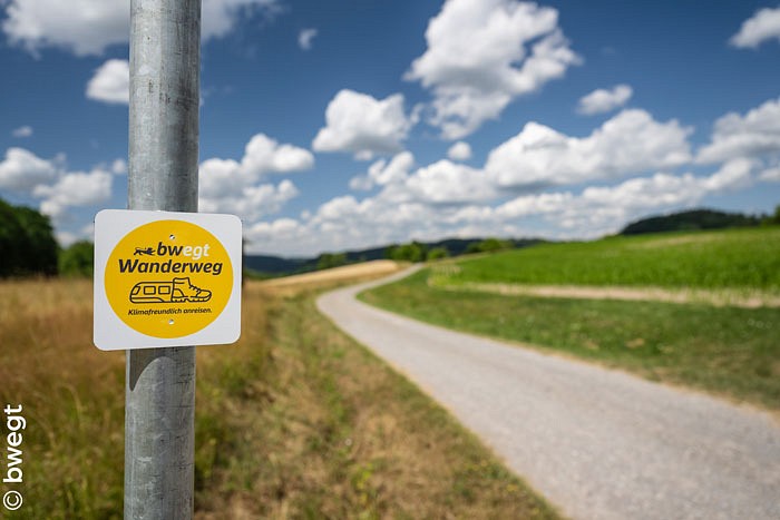 Gelbes Schild an einem Wanderweg