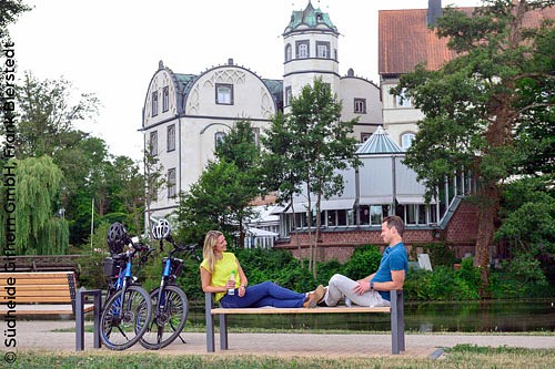 Zwei Radfahrende machen Pause auf einer Bank.