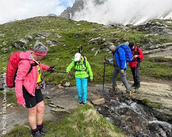 Eine Wandergruppe in den Bergen bei der Überquerung eines Bachs. 