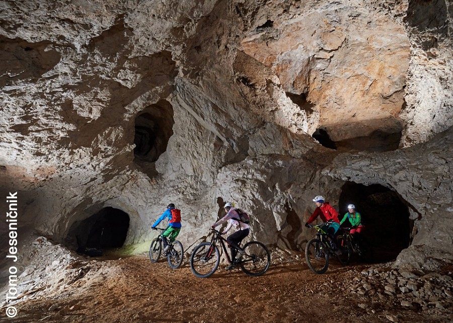 Mountainbiker:innen in einem Höhlengang unter Tage