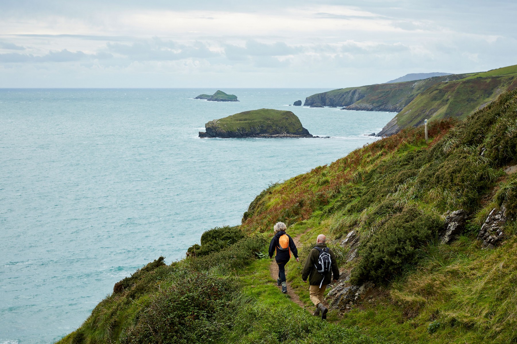 pstrongNon-Stopp-Kuumlstestrongbr-Der-1400-km-lange-a-hrefhttpswwwvisitwalescomdeinspirieren-sie-michgute-gruende-die-fuer-den-wales-coast-path-sprechen-targetblankWales-Coast-Patha-feiert-10-jaumlhriges-Jubliaumlum-Zerkluumlftete-Kuumlsten-und-das-weite-satte-Gruumln-der-umliegenden-huumlgeligen-Wiesenlandschaften-verfuumlhren-Wandernde-zum-Traumlumenp