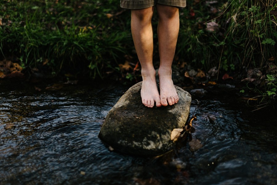 Zwei Füße auf einem Stein am Flussbett