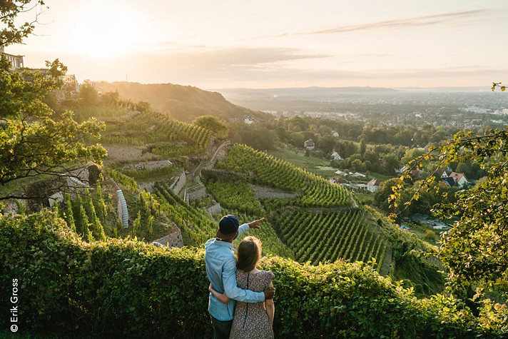 Ein Paar blickt auf terrassierte Weinhänge im Abendlicht.