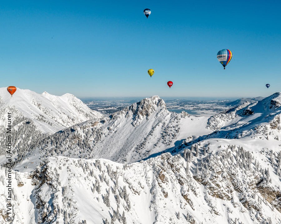 Heißluftballons über einer verschneiten Bergkette
