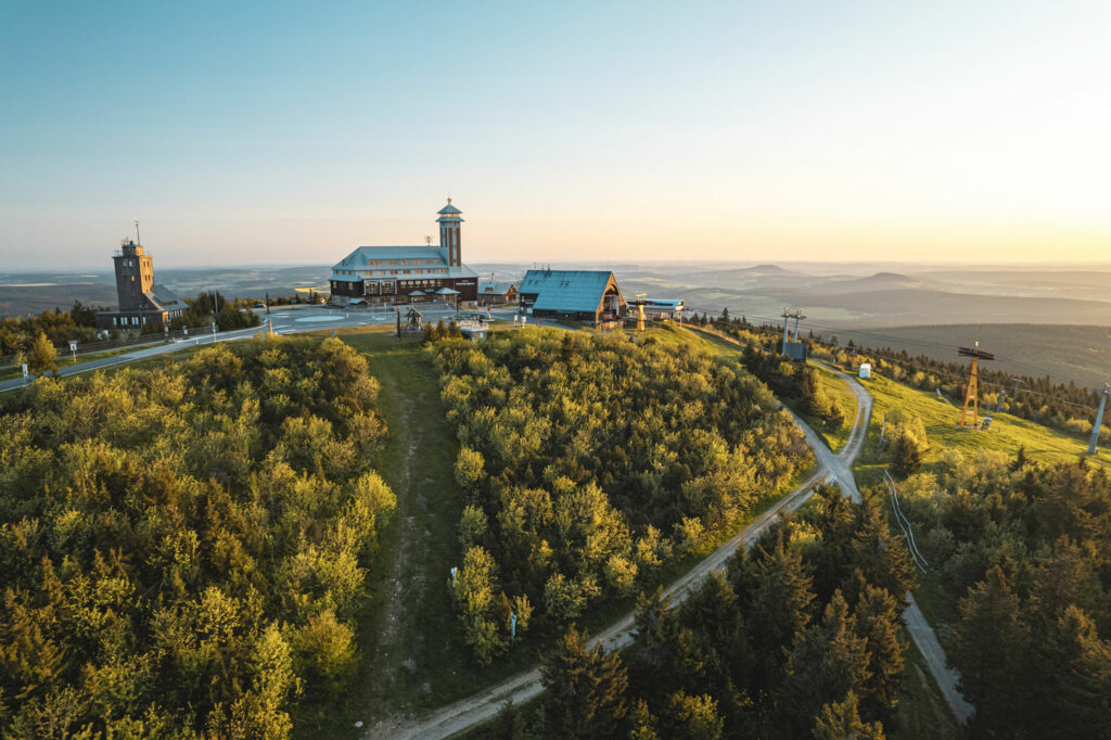 Ein Gebäude mit Turm thront auf einem grünen Hügel in der Abendsonne
