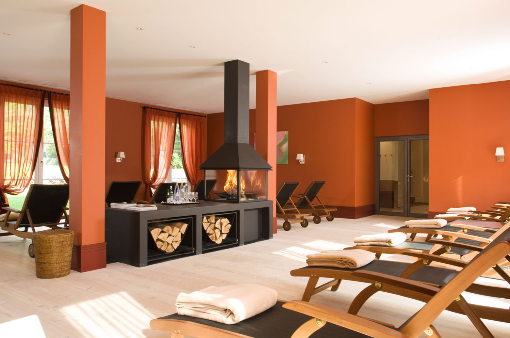 Ein rotes Zimmer mit Kamin und Liegen.