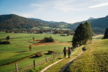 Zwei Wanderer auf einem Wiesenpfad in offener Berglandschaft