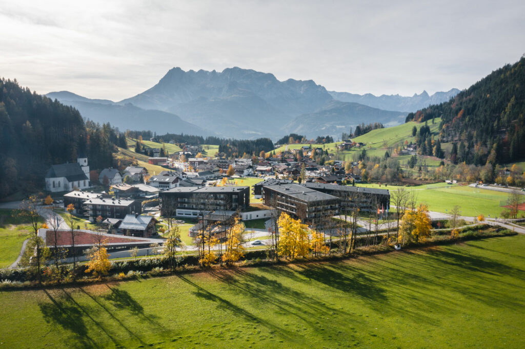 Vor einem Bergmassiv am Horizont liegen eine Ortschaft und vier markantere Hotelgebäude