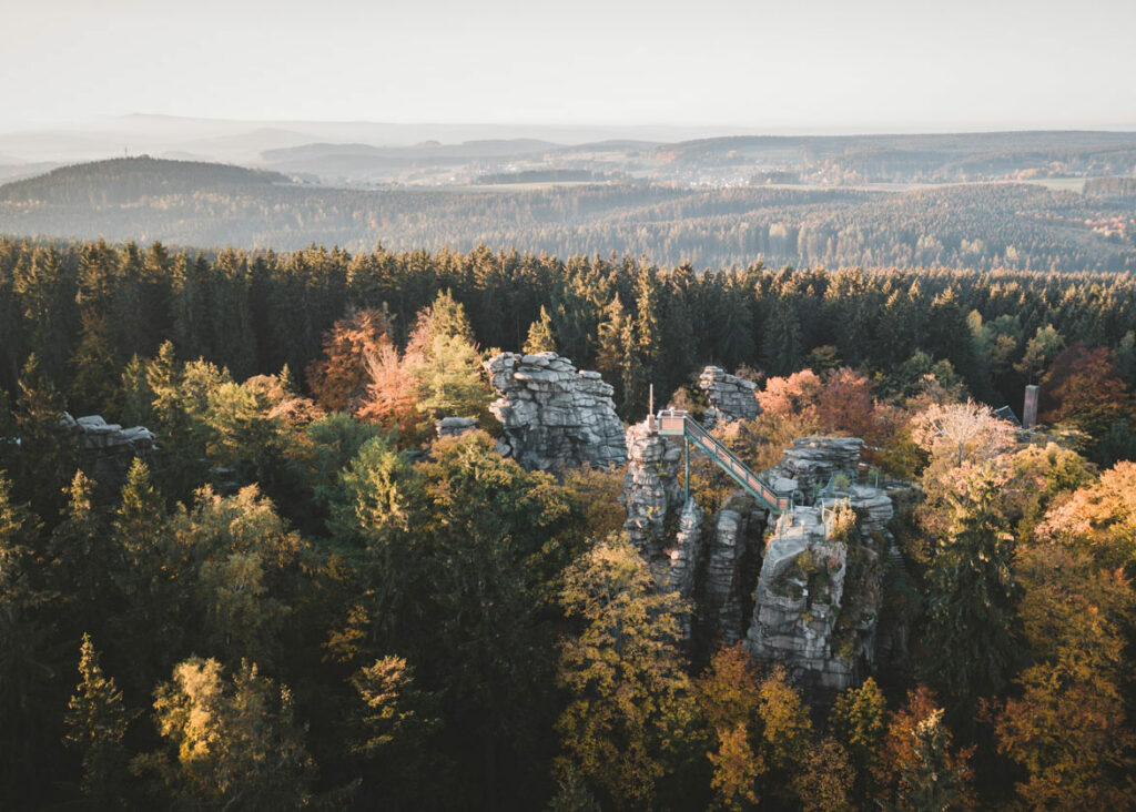 Blick auf graue Felstürme in einer weiten herbstlichen Waldlandschaft