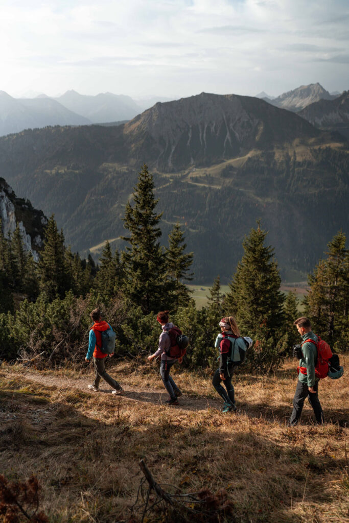 Wandergruppe im herbstlichen Waldhang und freier Sicht in ein Tal.