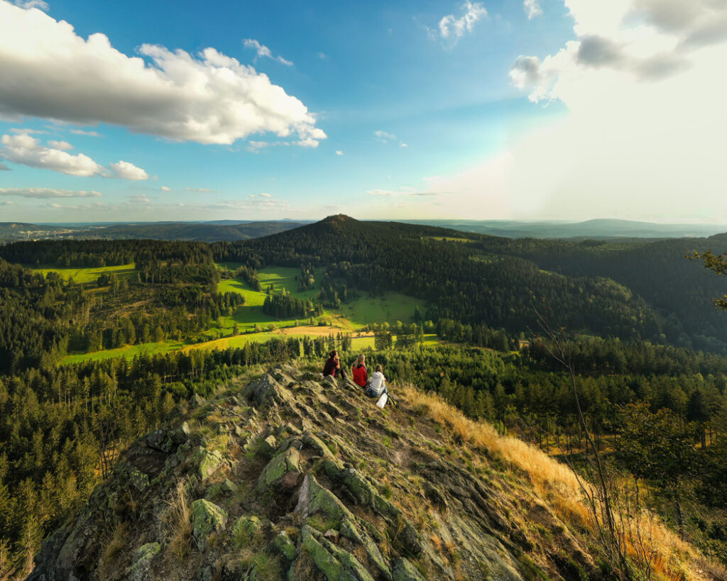Weitblick auf eine Menschengruppe auf einem Fels und das hügelige, waldige Umland