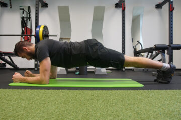 Marwin Isenberg macht eine rückenstärkende Übunge auf dem Boden im Fitnessstudio